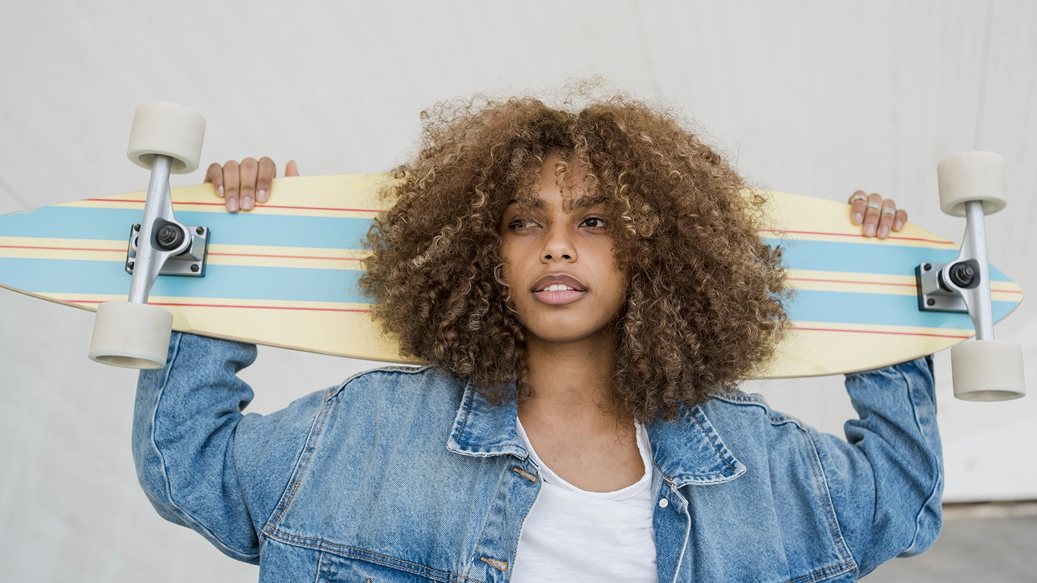 kobieta z burzą ciemnych loków i deskorolką