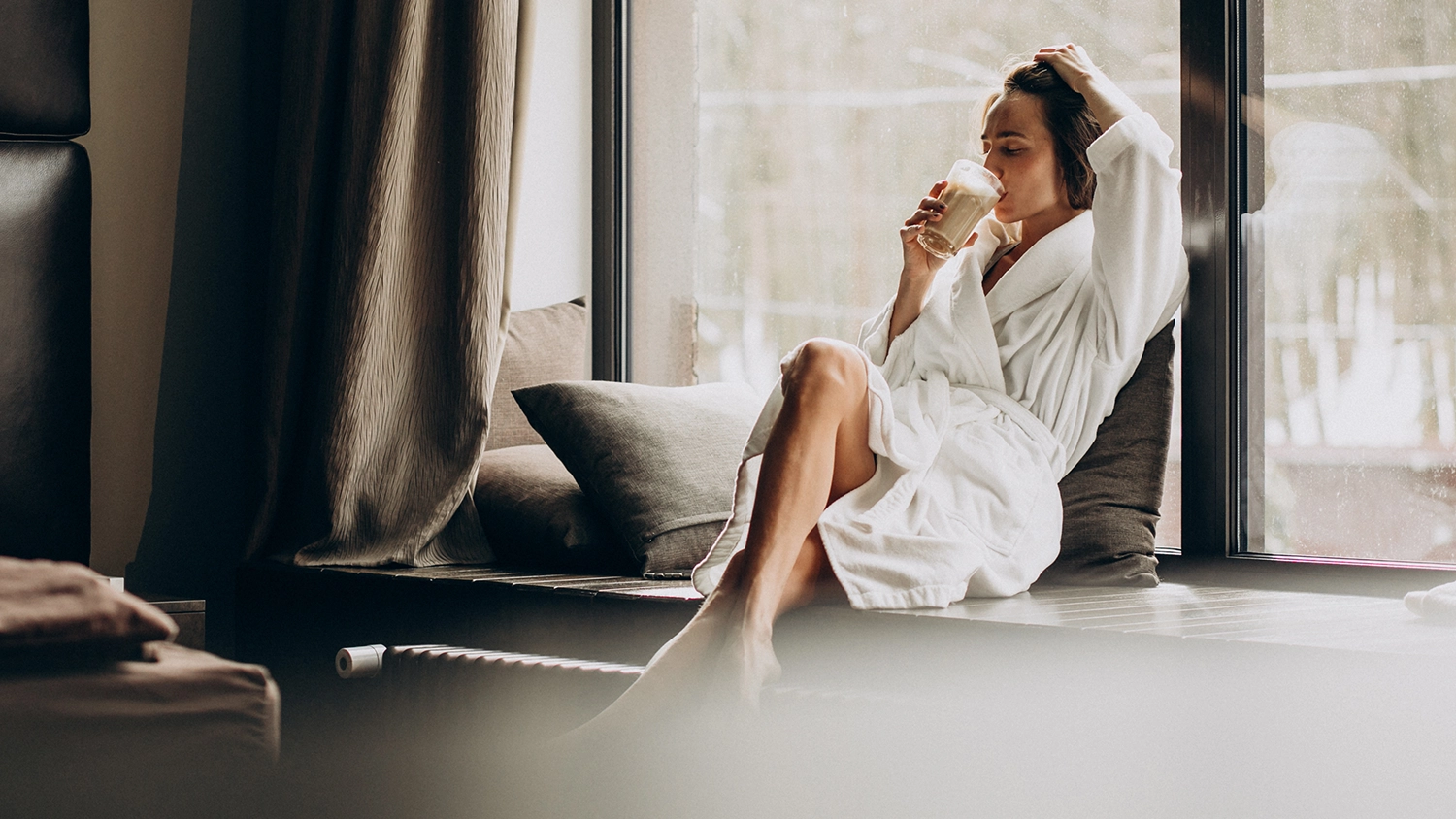 woman-drinking-coffee-bathrobe-by-window-home